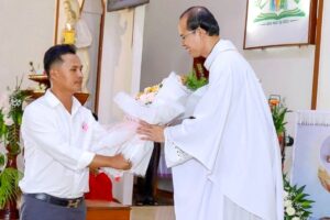 Ho reçoit des fleurs de la part du père Jean de la Croix Hoang Quang Hai à l’église de Hong Ha, le 14 décembre 2023.