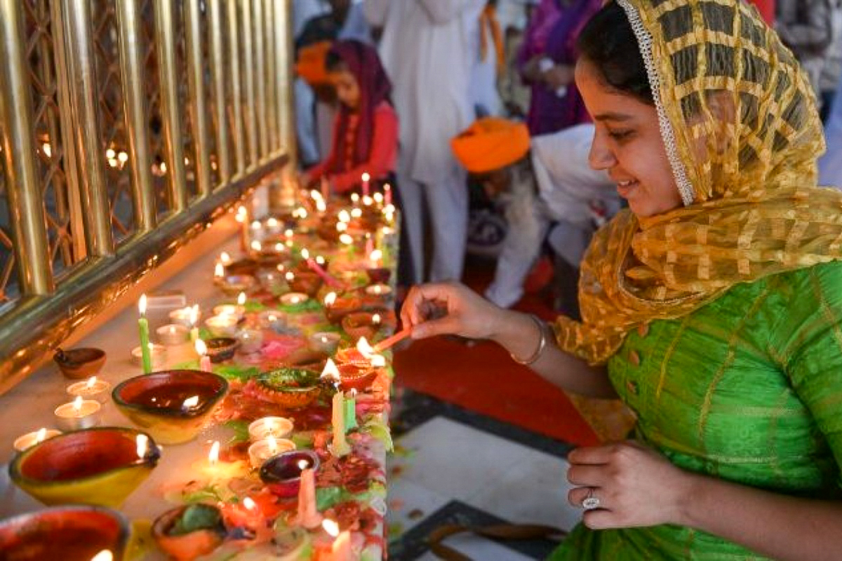 Des hindous allumant des lampes à huile durant la fête de Diwali.