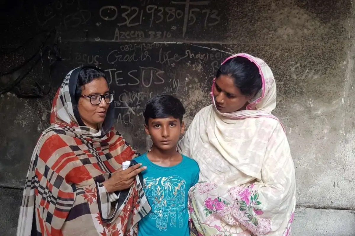 Slavish Murad, 10 ans, un élève chrétien de Jaranwala, avec sa mère et sa tente devant leur maison incendiée lors des émeutes en août 2023 au Pendjab.
