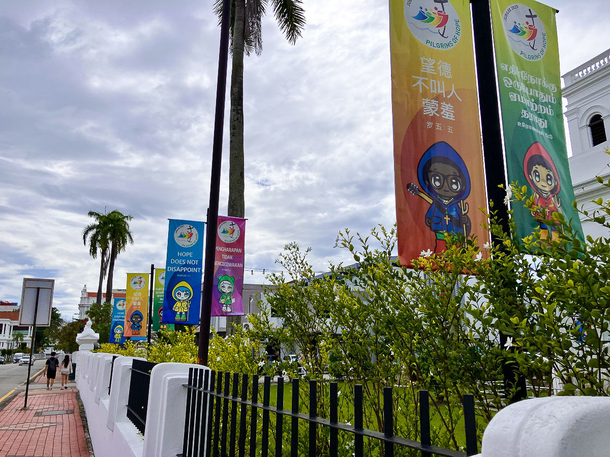 Différentes bannière aux couleurs du Jubilé 2025 sur les pèlerins d’espérance, devant une église de Georgetown, Penang, Malaisie.