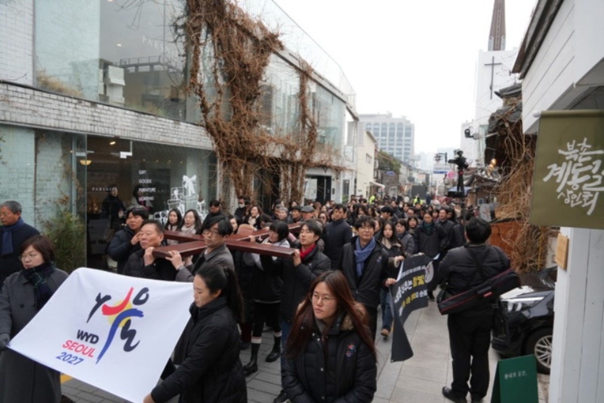 Des pèlerins portant la Croix des JMJ en procession devant l’église de Gahoedong (Séoul), le 28 décembre 2025.