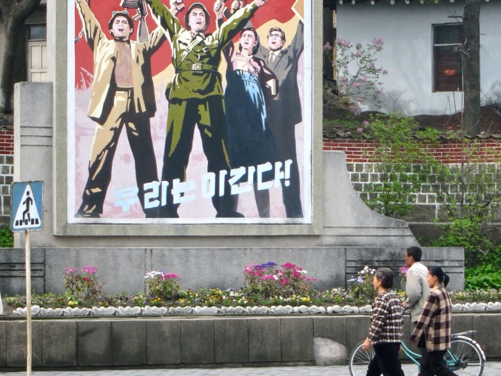 Des passants devant une affiche de propagande à Kaesong, en Corée du Nord.
