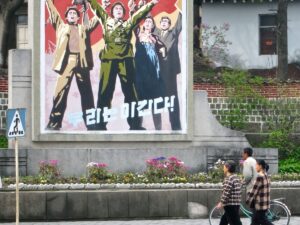 Des passants devant une affiche de propagande à Kaesong, en Corée du Nord.