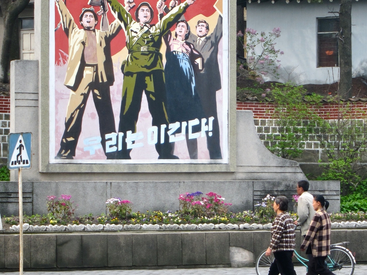 Des passants devant une affiche de propagande à Kaesong, en Corée du Nord.