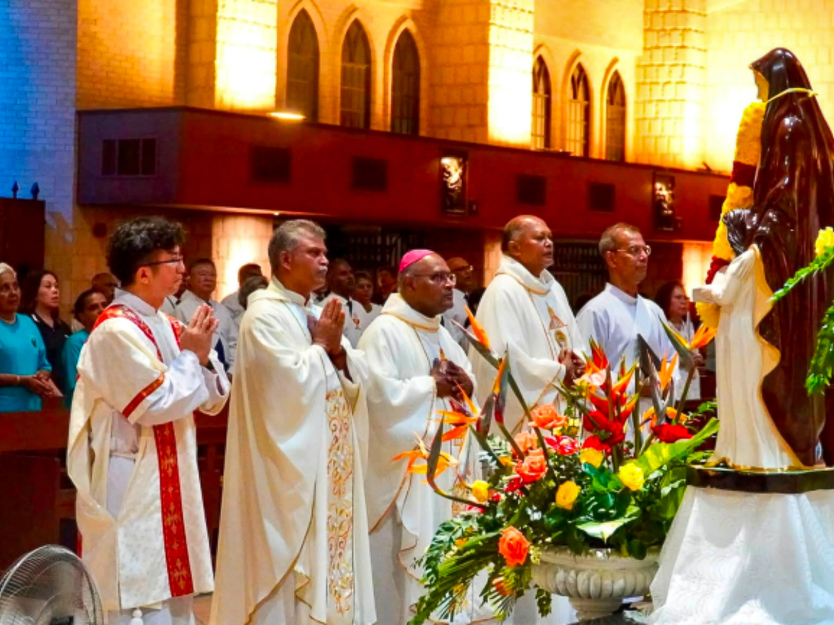 Des membres du clergé prient devant la statue de sainte Anne dans la basilique de Bukit Mertajam, Penang, Malaisie.