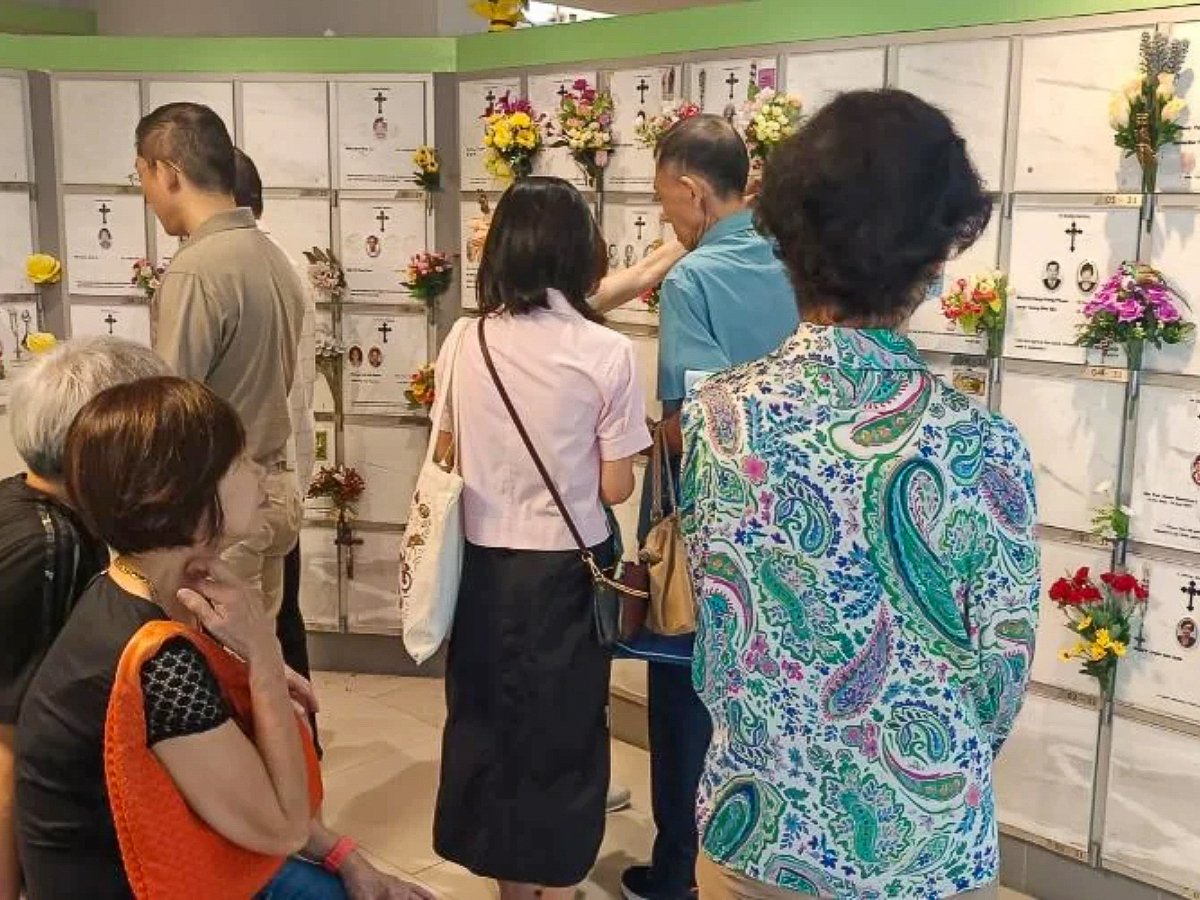 Des catholiques se recueillent devant les niches funéraires de leurs proches au columbarium de l’église Saints-Pierre-et-Paul de Singapour, le jour des défunts 2024.